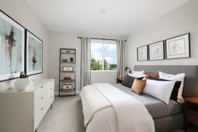 Bright bedroom featuring a cozy bed and large window with natural light.