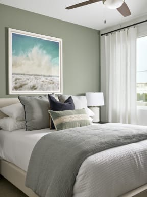 a bedroom with a bed with pillows and a painting on the wall above it