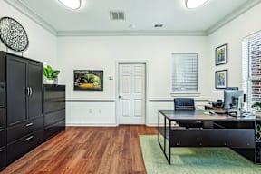 A black desk with a computer and chair in a room with a white door.