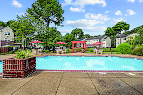 A pool surrounded by a red fence and trees.