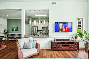 A living room with a grey couch and a television on the wall.