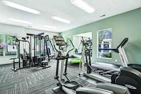 A gym with a variety of equipment including treadmills, weights, and exercise machines.