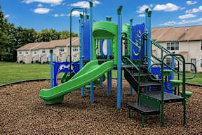 A playground with a green slide and a blue structure.