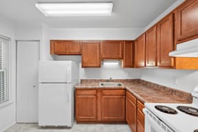 A kitchen with brown cabinets and a white refrigerator.