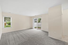 A room with a carpeted floor and a window showing a view of a house and a fence.