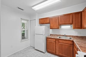 A kitchen with white appliances and brown cabinets.