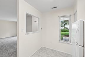 A white refrigerator sits in a kitchen next to a window.