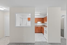 A kitchen with white walls and wooden cabinets.