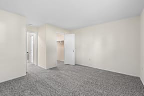 A large empty room with carpeted floor and white walls.