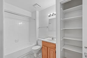 A white bathroom with a toilet, sink, and shelves.