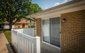 A white picket fence in front of a brick house.