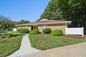 A house with a white picket fence and green bushes in front.