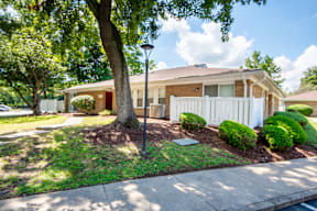 A house with a white picket fence and a tree in front.