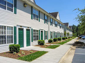 a long white building with green doors and shutters