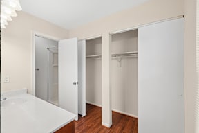 A white bathroom with a sink and three open closets.