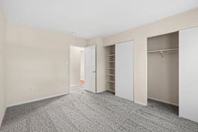 A room with a carpeted floor and white closet doors.
