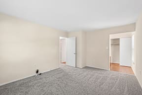 A room with a carpeted floor and two open doors.