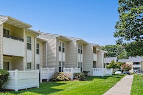 A row of white apartment buildings with green lawns in front.
