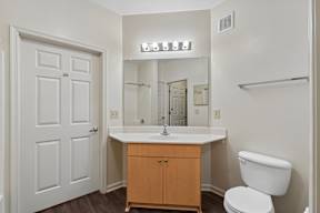 A white bathroom with a toilet, sink, and mirror.