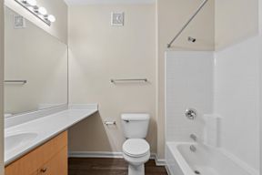 A white toilet sits next to a white bathtub in a bathroom.