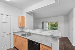 A kitchen with a white counter top and wooden cabinets.