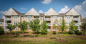 Apartment complex with multiple buildings and green trees in front.