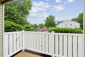 A white fence in front of a house and trees.