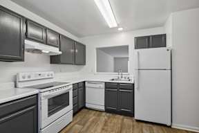 A kitchen with black cabinets and white appliances.
