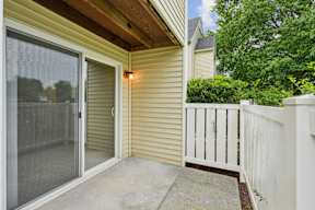 A patio with a sliding glass door and a white fence.
