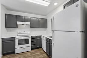 A white refrigerator stands in a kitchen with black cabinets.