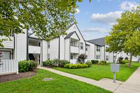 Apartment complex with a white fence and green trees.