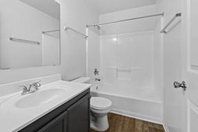 A white bathroom with a toilet, sink, and shower.
