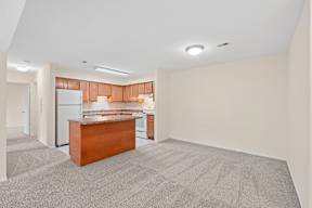 A kitchen with a brown island in the middle of a room with carpet.