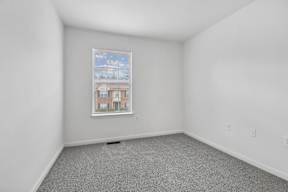 A room with a window showing a view of a building.