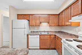 A kitchen with brown cabinets and a white refrigerator.