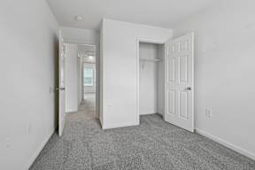 A long hallway with white walls and a carpeted floor.