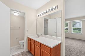 A bathroom with a white countertop and brown cabinets.