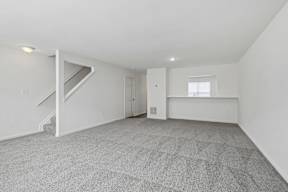 A spacious room with a staircase and a window.