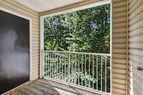 A balcony with a white railing and a view of trees.