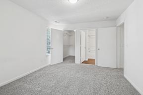 A white room with a grey carpet and a window with blinds.