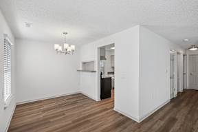 A white room with wood flooring and a chandelier.
