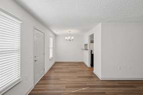 A long, empty hallway with white walls and wood flooring.