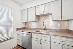 A kitchen with white cabinets and a tiled backsplash.