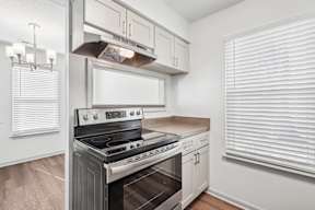 A modern kitchen with a stainless steel oven and white cabinets.