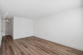 A room with wooden flooring and white walls.