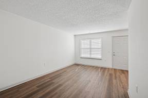 A room with wooden flooring and a window with blinds.