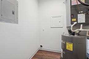 A utility room with a furnace and a white electrical box on the wall.