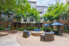 a courtyard with tables and umbrellas in front of an apartment building