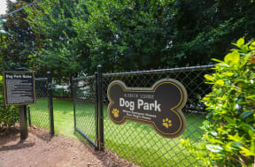a sign for dog park in front of a fence
