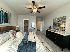 A bedroom with a large bed and a ceiling fan.